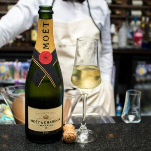 Elegant Moët & Chandon champagne bottle and glass at a festive bar setting.